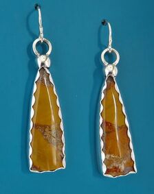 Sterling silver handmade earrings with wavy-edge bezels around long triangles of yellow jasper on turquoise background