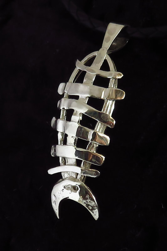 Sterling silver handmade pendant of fish skeleton against black background