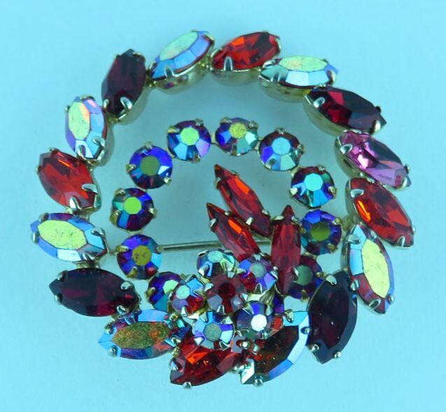 Brooch with circular design of colored stones on blue background