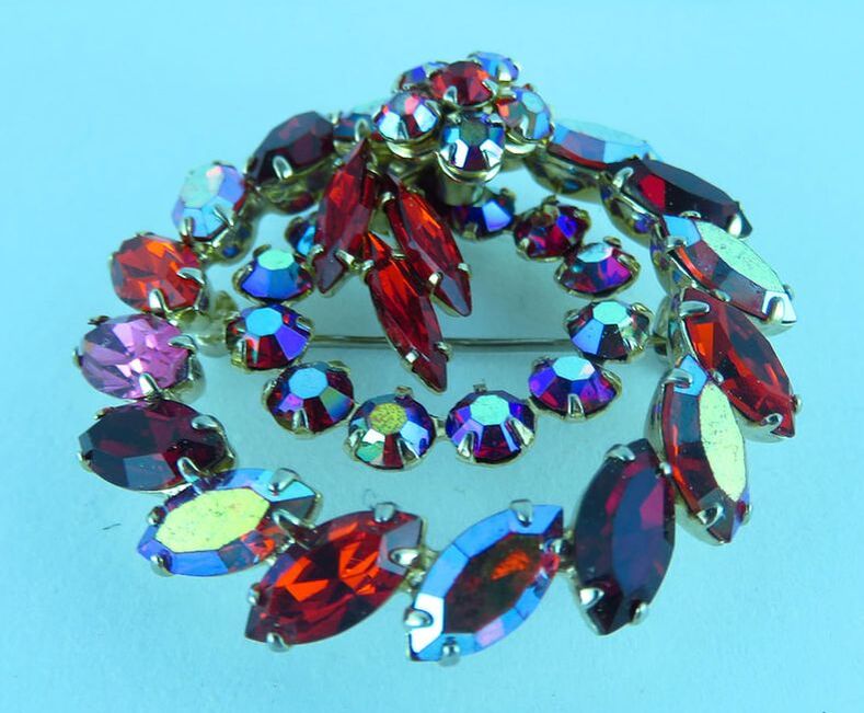 Brooch of colored Swarovski crystal stones with circular design on blue background